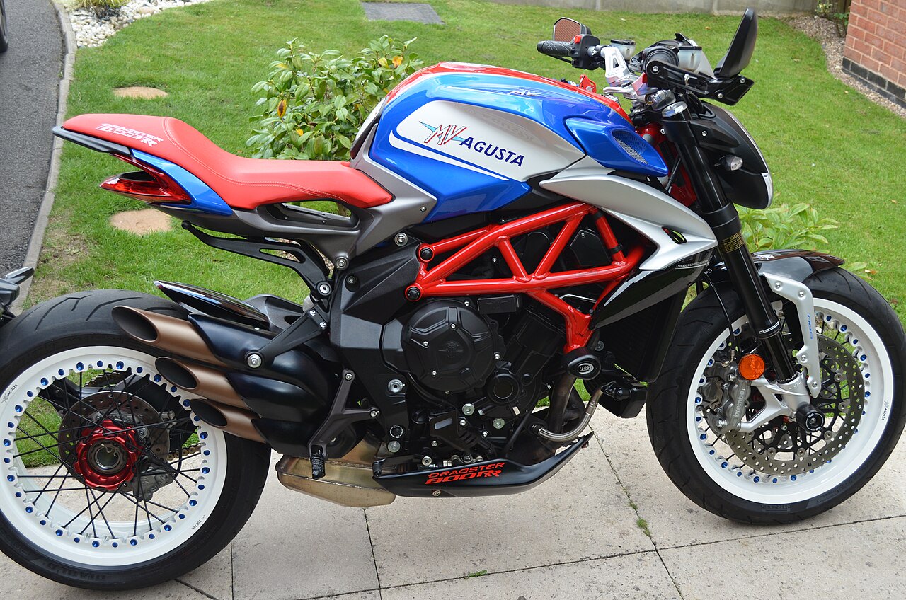 אופנוע MV Agusta Dragster 800RR בצבעי כחול, אדום ולבן, צילום צד מקרוב על סלולית, ברקע דשא וצמחייה