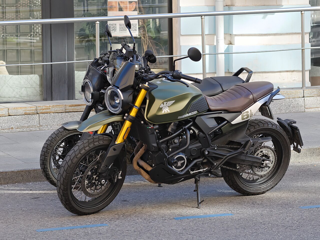אופנוע Semmezzo 618 בצבע ירוק-חזה עם מוטות צהובים, צילום צד של שני אופנועים עמידים על המדרכה מול חנות, רקע עירוני