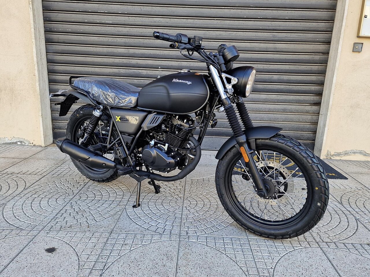 אופנוע Harley Davidson X-Light 125 בצבע שחור, צילום צד מימין מול שער גלגלים, מושב מוסתר בפלסטיק