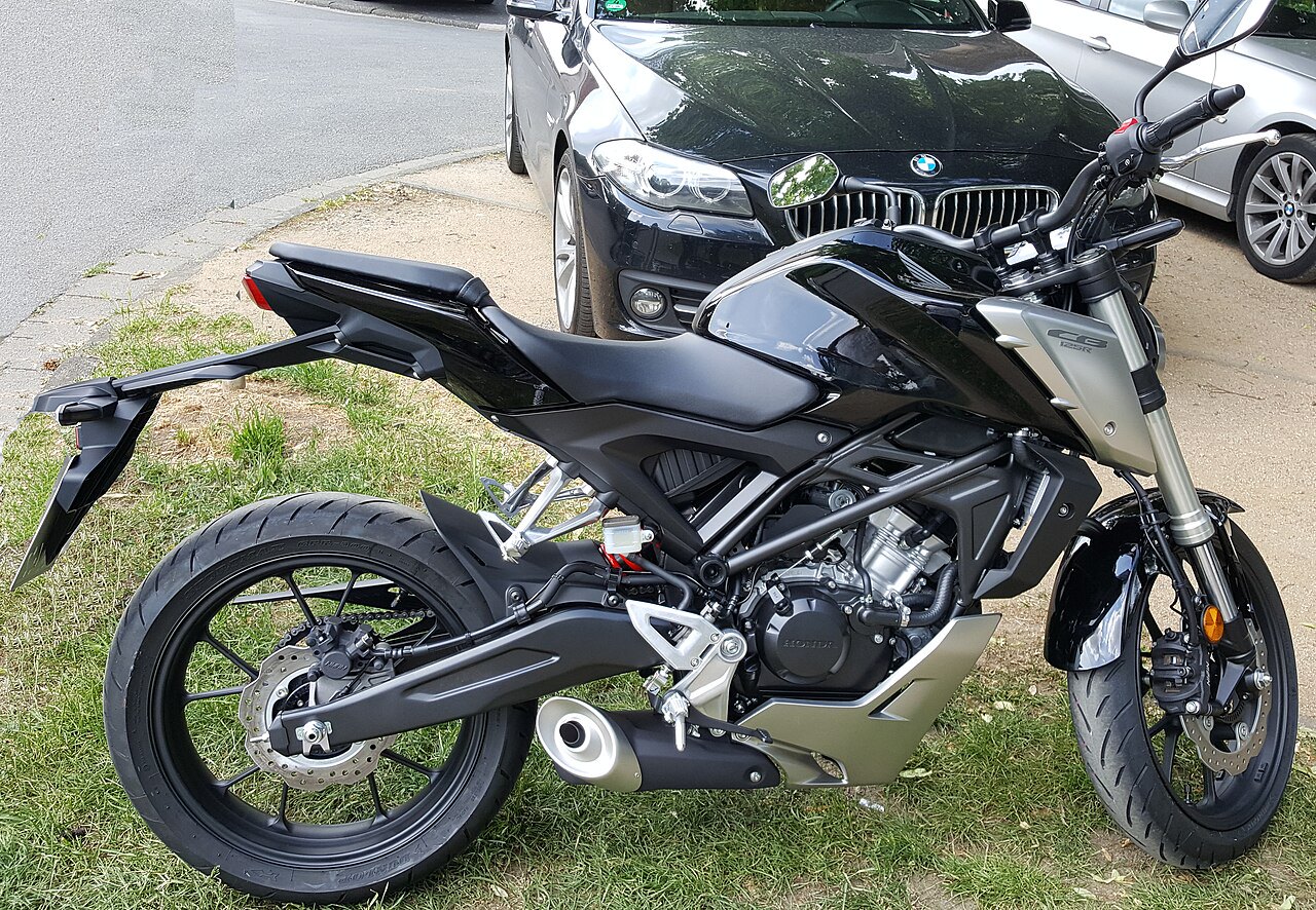 אופנוע הונדה CB300R שחור-כסוף, צילום צד, על עשב ליד רכב BMW שחור