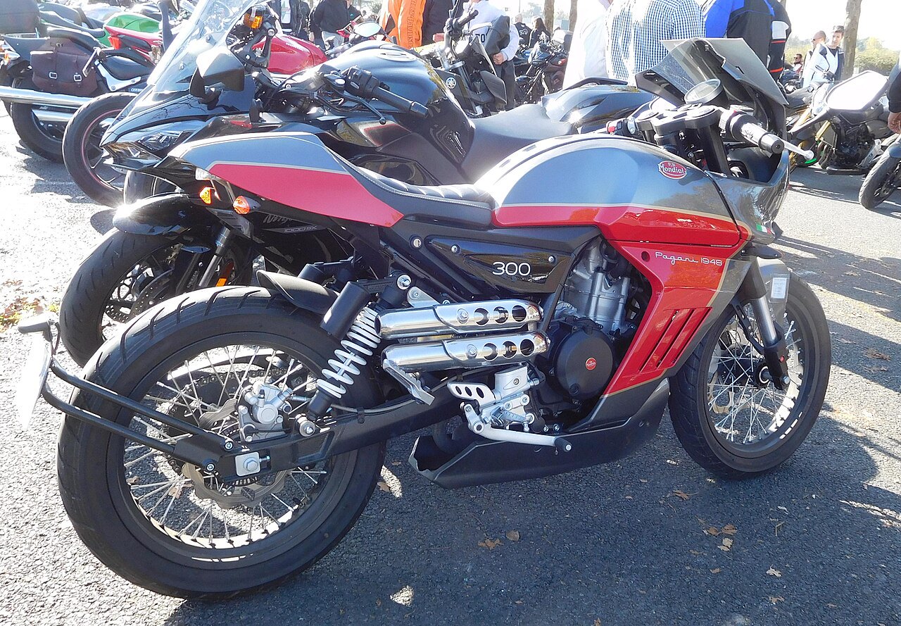 אופנוע מוטורסיקלט אדום-שחור של מותג Mondial דגם Pagan 1948, מנוע 300, צילום צד מקרוב בפארק אופנועים חיצוני.