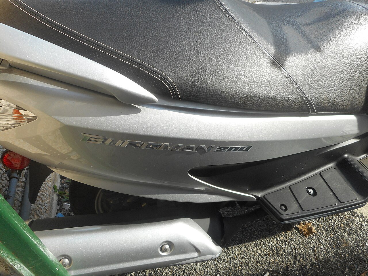 אופנוע ס쿠וטר Burman 200 בצבע אפור, צילום קרוב של מושב וגוף, על רקע אספלט.