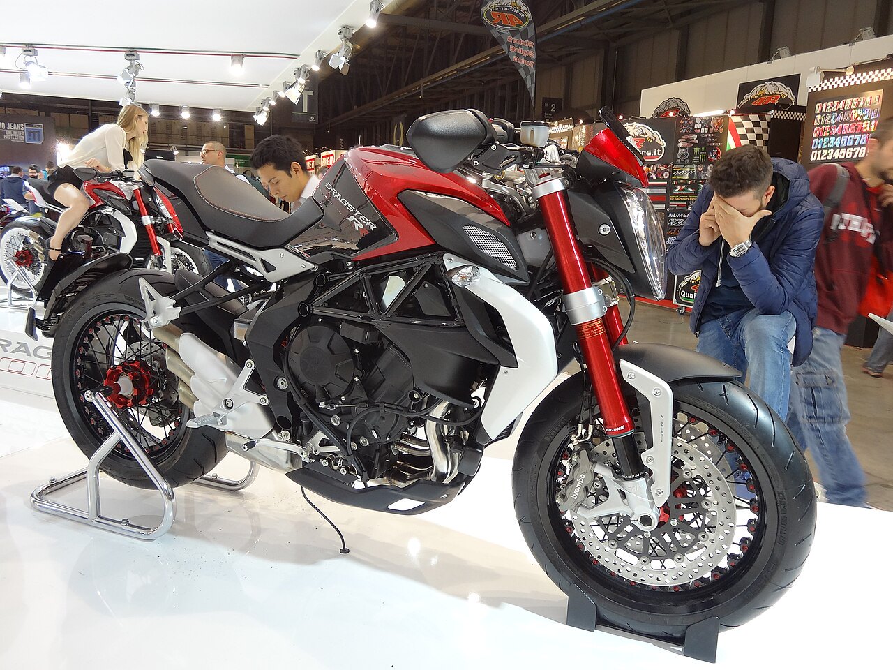 אופנוע Ducati Diavel 1260 S אדום-שחור בתצוגה, צילום צד, עם מבקרים בסביבה