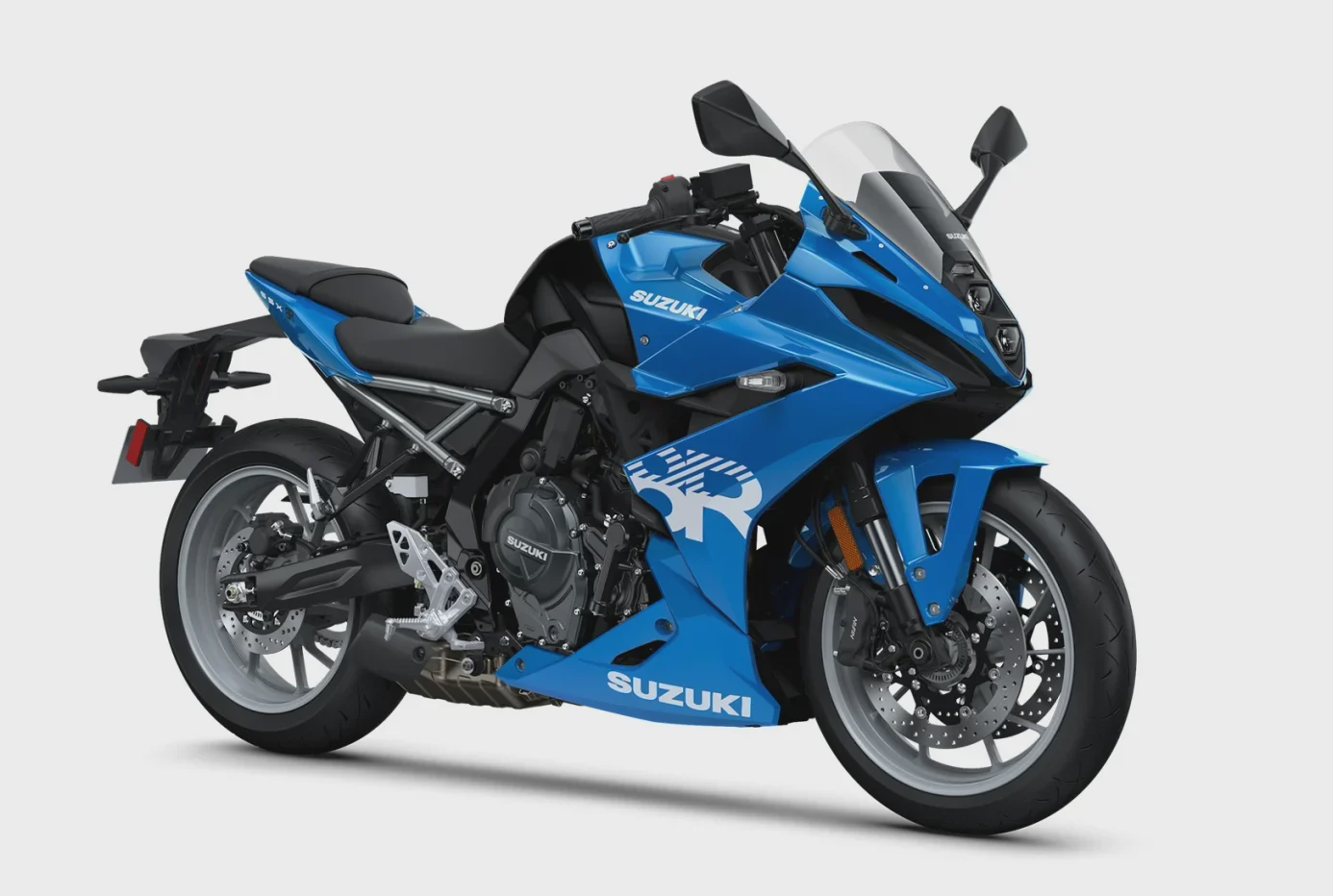 אופנוע סוזוקי GSX-S1000F כחול מבריק, צילום צד, מול מונומנט אבן עם פסלים, יום בהיר, אנשים ברקע