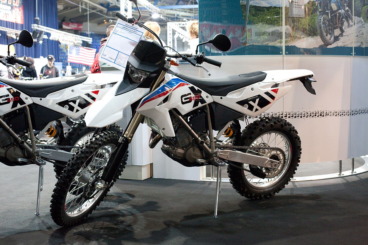 אופנועי GASGAS GX 450 לבנים עם פסים אדומים וכחולים, מוצגים בתצוגה פנימית עם מראה אופנועים ורקע של דגל ארצות הברית.