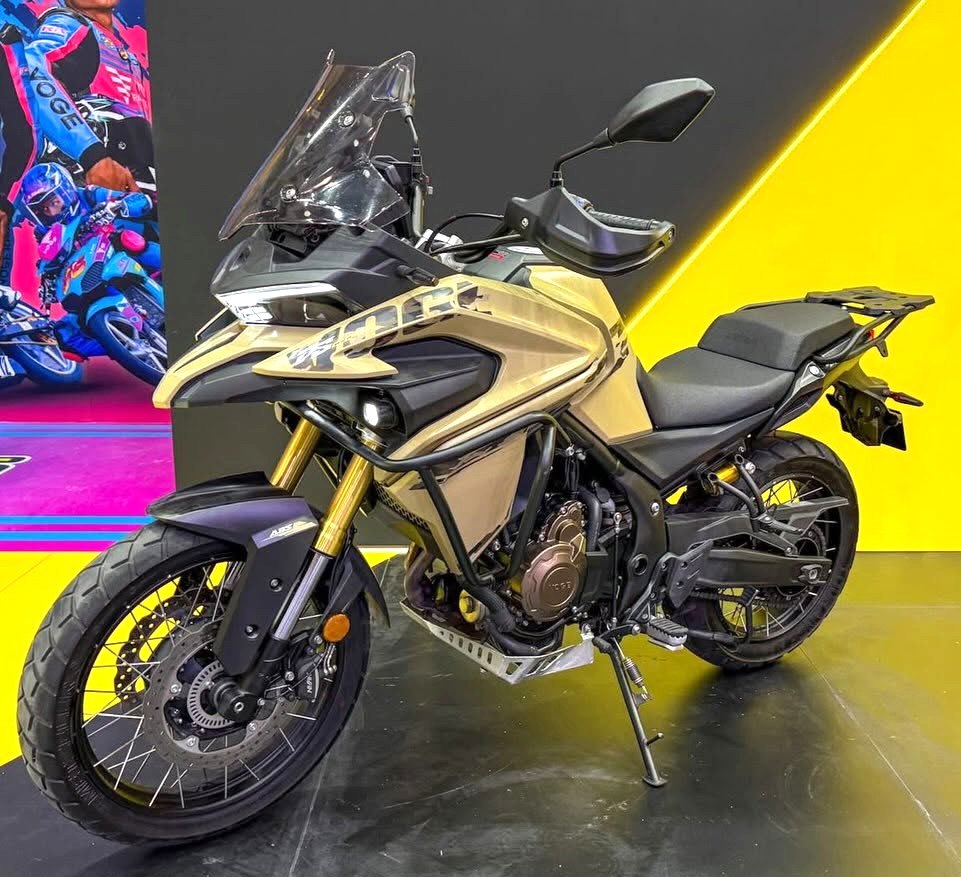אופנוע Kawasaki Versys 1000 בצבע זהב-שחור, צילום צד מזדמן, רקע צהוב-שחור עם פוסטר רכיבה