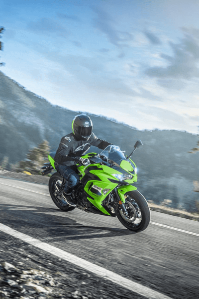 אופנוע Kawasaki ZX-6R ירוק בהיר, צילום צד, עם קסדה על הידית, בחצר עם שער מתכת ודלתות ירוקות