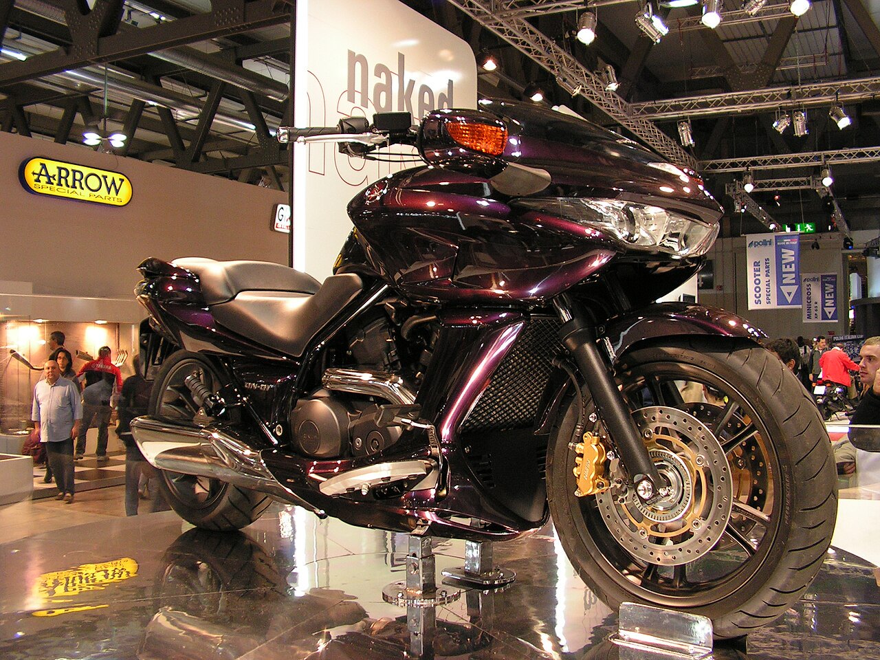 אופנוע Ducati Diavel בצבע סגול מבריק, צילום קרוב מזווית נמוכה על תצוגה בתערוכה, עם לוגו ARROW Special Parts ברקע