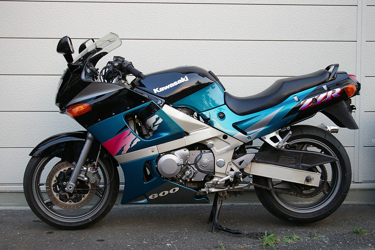 אופנוע קאוסקי ZX-600 בצבע כחול-שחור עם פסים ורודים, צילום צד, על רקע קיר לבן