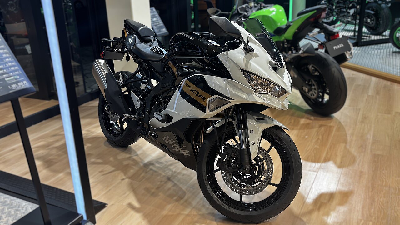 אופנוע Kawasaki Ninja ZX-4R לבן ושחור בתצוגה, זווית צד קדמית, מראה פנים חנות עם דגמים נוספים ברקע